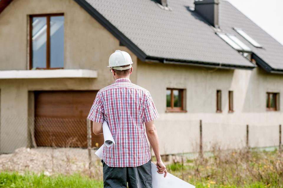 Builder reviewing plans at a home under construction