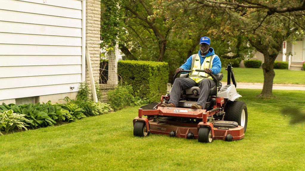 Crew member mowing a lawn on a riding mower